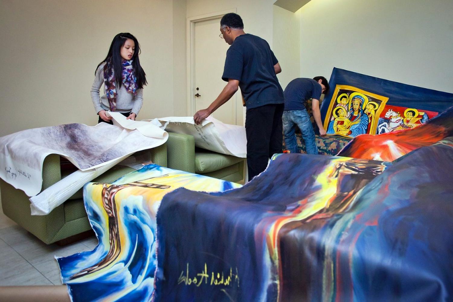 Adjunct Professor of Fine Arts Khalid Kodi with Art Club students, installing artwork in the Bapst Library gallery space. The artwork is related to a  project that relates to the principles and commitment to peaceful co-existence and social justice. 