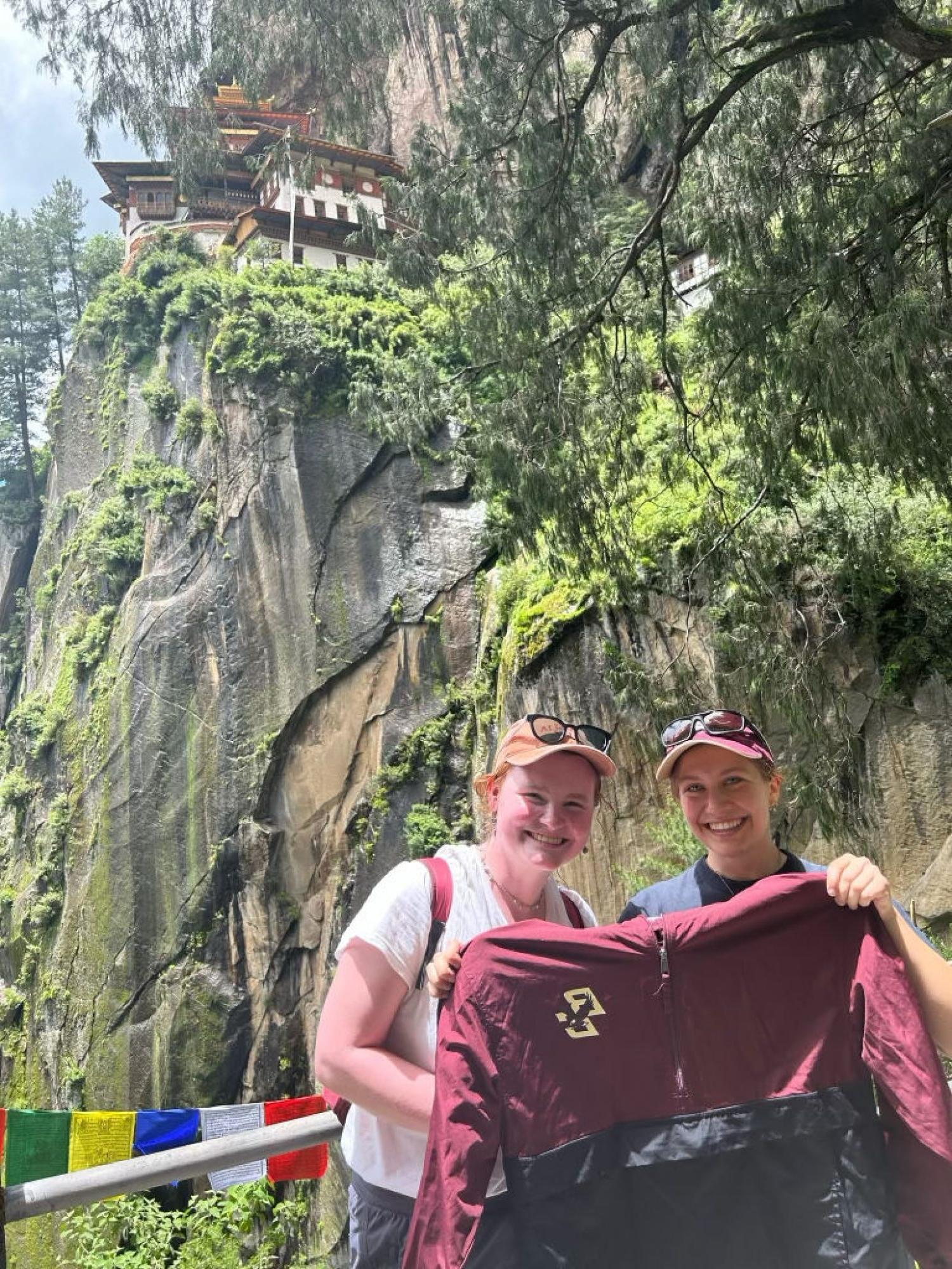 Two students holding a BC jacket near a temple